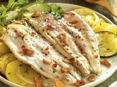 Ryba pečená v troubě se zeleninou ,posypaná restovaným česnekem .
